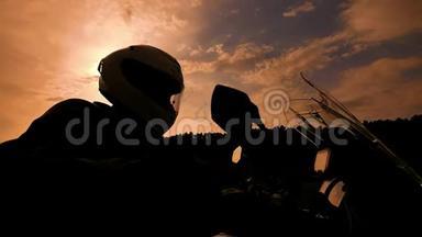 摩托车手在日落慢速运动启动他的摩托车